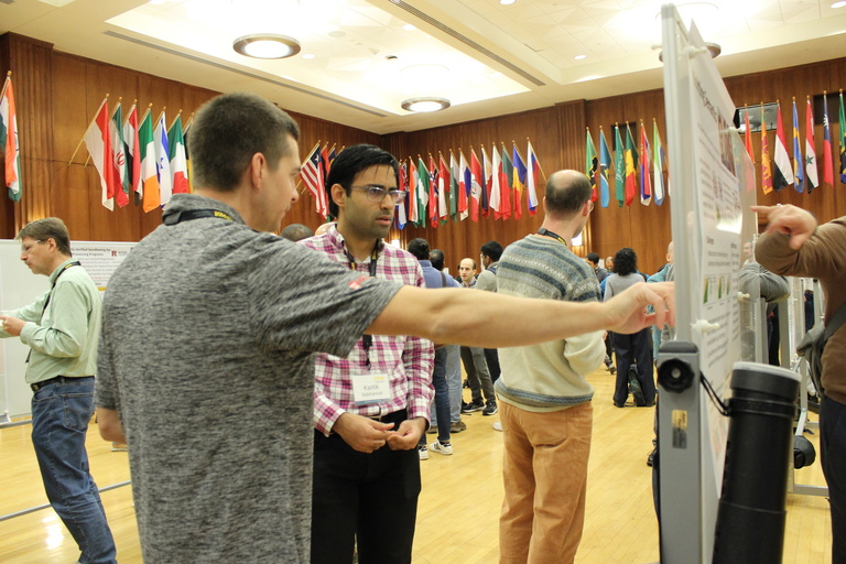Kartik Sabharwal listens while an attendee describes a poster hanging on a white board