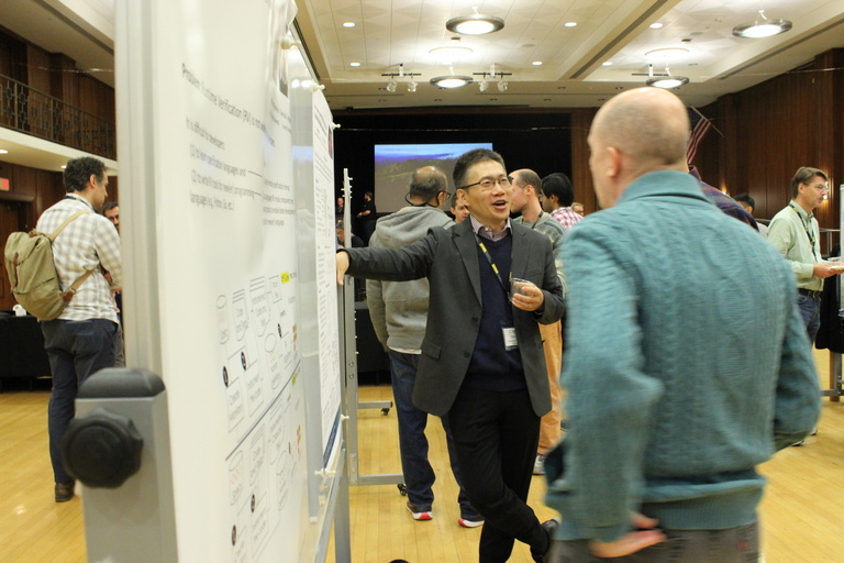 Chao Wang (University of Southern California) leans up against a whiteboard while socializes with another attendee during the meeting's poster session