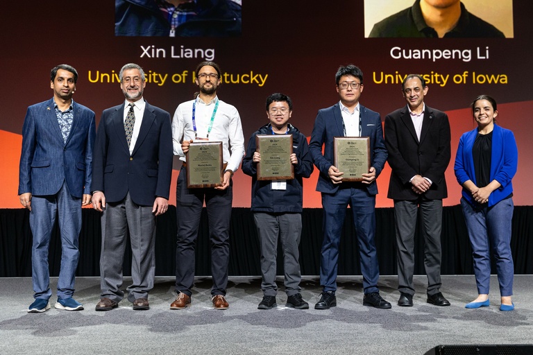 Li stands onstage at SC24 holding his Award for Excellence for Early Career Researchers in High Performance Computing