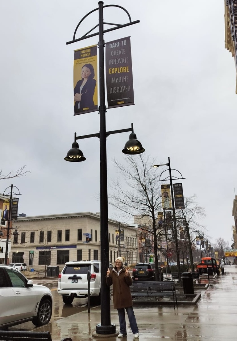 Phuong Nguyen stands in front of her Dare to Discover banner in downtown Iowa City. 