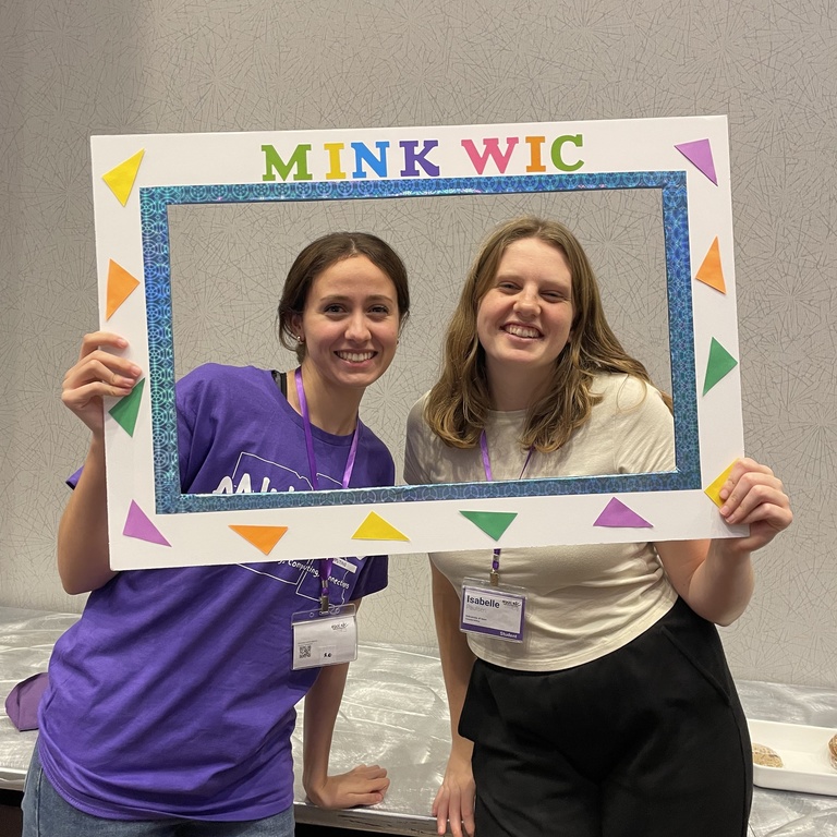 WiCS executives Isabelle Paulsen and Annalisa Karacay posing with for a portrait with MINK WIC "frame"