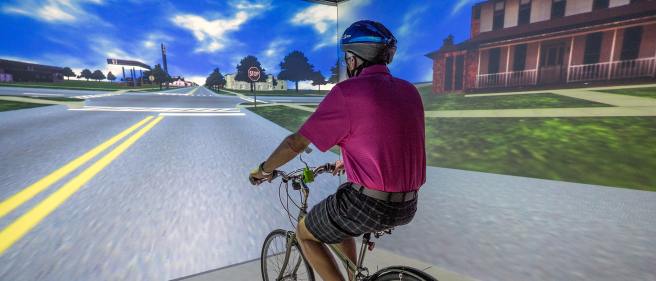 A older man riding a stationary bicycle in the HANK Virtual Environments Lab