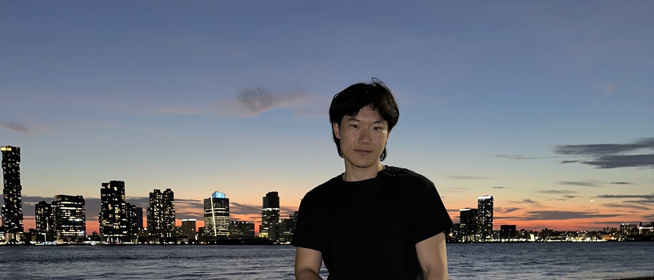 Zhu standing in front of the New York City skyline during sunset
