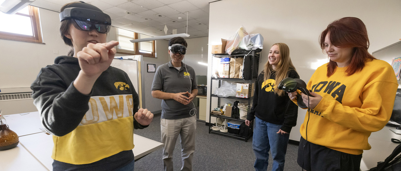 three students test out virtual reality equipment with their professor