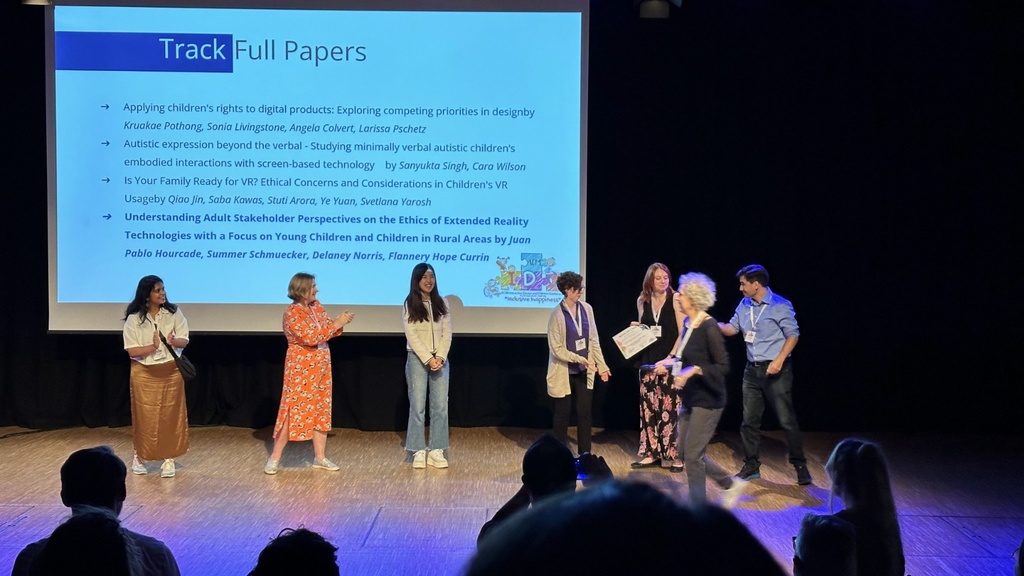 Health and wellness Computer-Human Interaction (HawCHI) Lab members receiving Best Paper award during conference. Other contenders also on stage. 