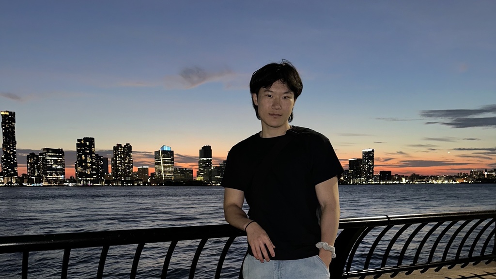 Zhu standing in front of the New York City skyline during sunset
